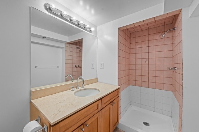 bathroom with tiled shower and vanity