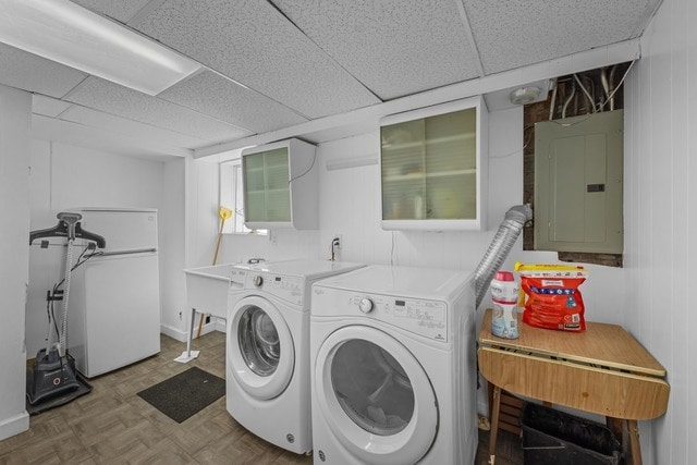 laundry area featuring electric panel, parquet flooring, wood walls, and washing machine and clothes dryer