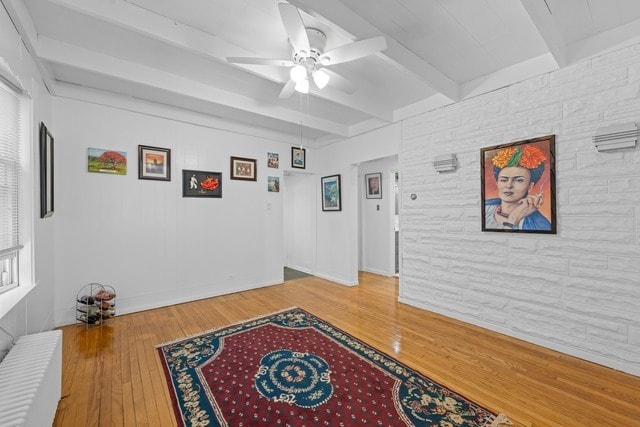 sitting room with wood-type flooring, beamed ceiling, and ceiling fan