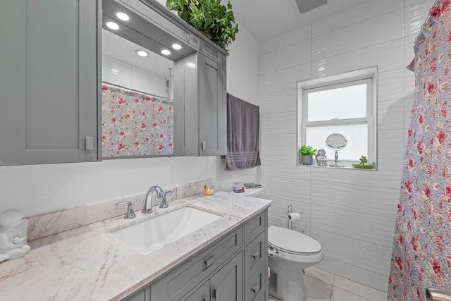 bathroom featuring tile patterned flooring, curtained shower, vanity, and toilet