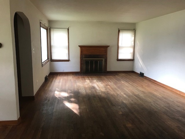 unfurnished living room featuring a fireplace, dark hardwood / wood-style floors, and a wealth of natural light