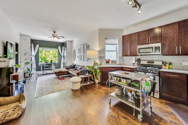 kitchen with dark hardwood / wood-style flooring, appliances with stainless steel finishes, ceiling fan, and tasteful backsplash