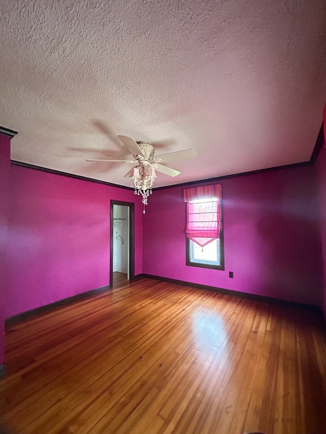 unfurnished room featuring ceiling fan, hardwood / wood-style flooring, crown molding, and a textured ceiling