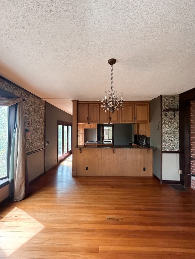 kitchen featuring kitchen peninsula, hanging light fixtures, a chandelier, and light wood-type flooring