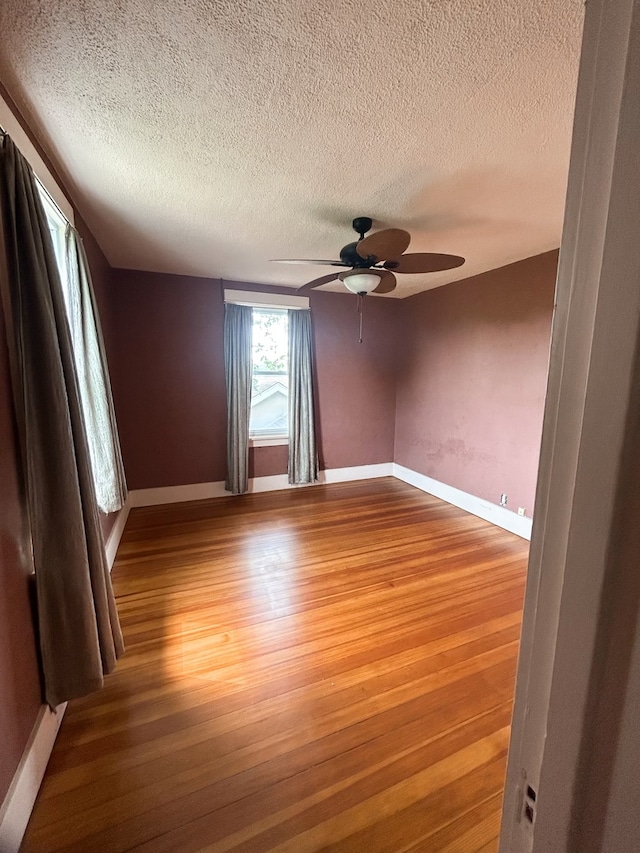 unfurnished room featuring ceiling fan, hardwood / wood-style flooring, and a textured ceiling