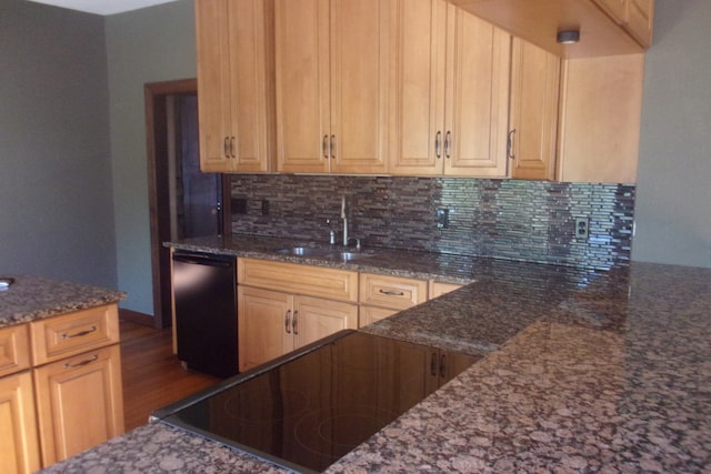 kitchen featuring decorative backsplash, hardwood / wood-style flooring, sink, dark stone counters, and dishwasher