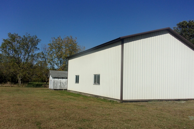 view of side of property featuring a lawn and an outbuilding