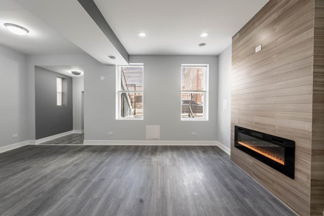 unfurnished living room featuring dark wood-type flooring and a fireplace