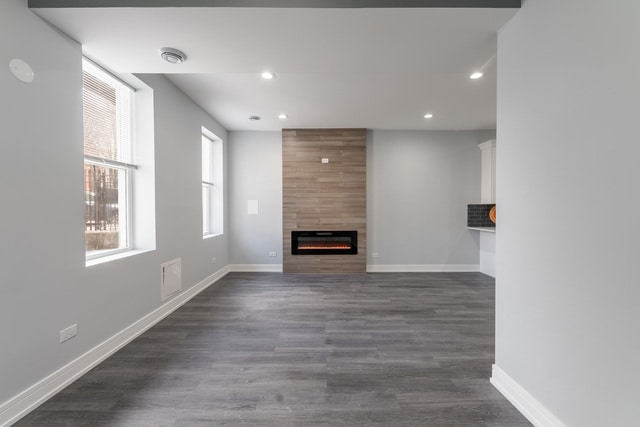 unfurnished living room featuring dark wood-type flooring and a tile fireplace