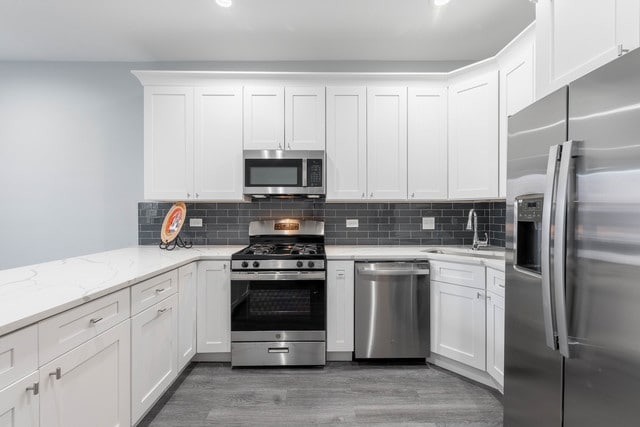 kitchen featuring appliances with stainless steel finishes, dark wood-type flooring, sink, and white cabinets