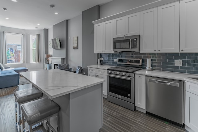 kitchen with appliances with stainless steel finishes, a kitchen island, a breakfast bar, and white cabinets