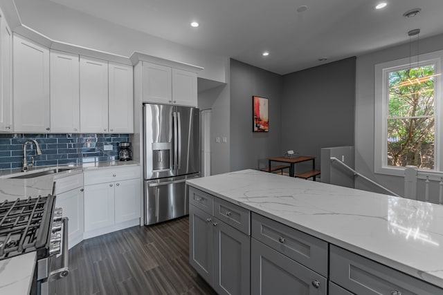 kitchen featuring decorative light fixtures, sink, stainless steel appliances, light stone countertops, and white cabinets