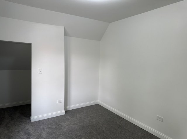 carpeted empty room featuring vaulted ceiling