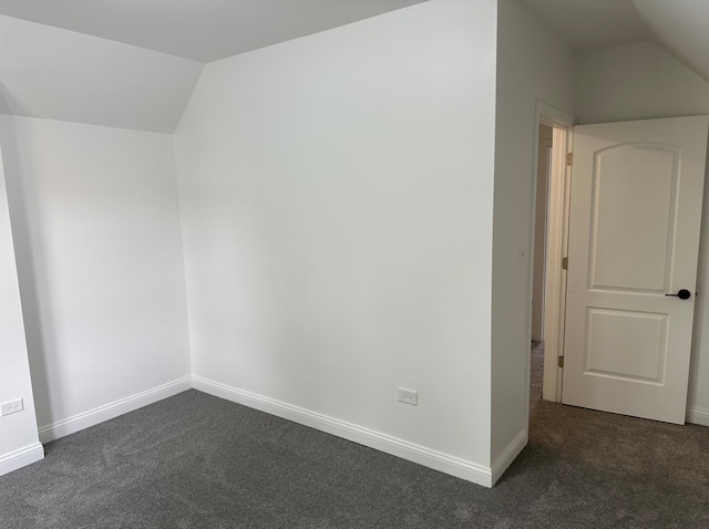 additional living space featuring dark carpet and vaulted ceiling