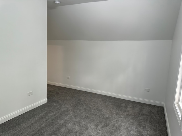 bonus room featuring lofted ceiling and dark colored carpet