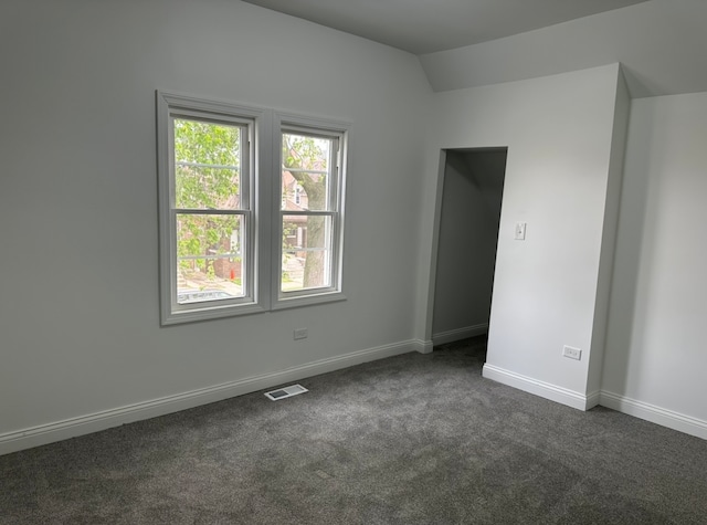 unfurnished room with lofted ceiling and dark carpet