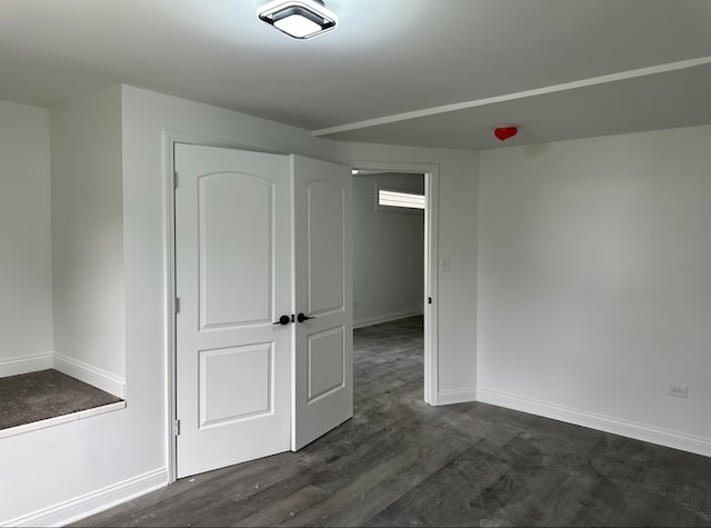 unfurnished room with dark wood-type flooring