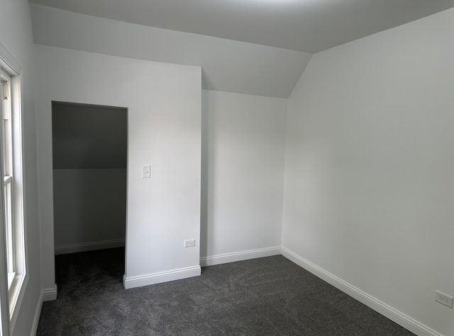 empty room featuring dark carpet and vaulted ceiling