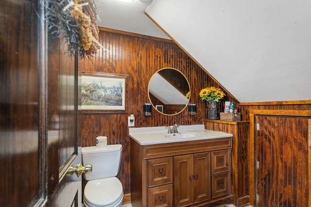 bathroom featuring lofted ceiling, wooden walls, vanity, and toilet