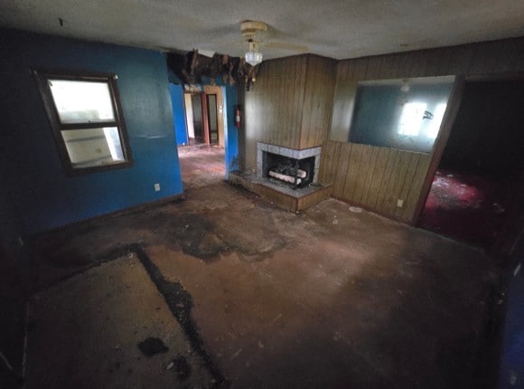 unfurnished living room featuring a multi sided fireplace and wood walls