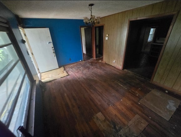 unfurnished dining area with dark hardwood / wood-style floors, an inviting chandelier, and a textured ceiling