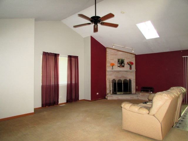 unfurnished living room featuring light carpet, vaulted ceiling with skylight, a brick fireplace, and ceiling fan