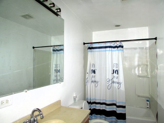 full bathroom featuring vanity, shower / bath combination with curtain, and toilet