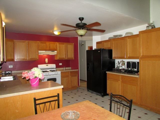 kitchen with sink, white gas range oven, black refrigerator with ice dispenser, kitchen peninsula, and ceiling fan