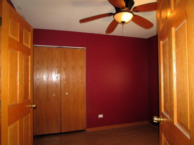 unfurnished bedroom featuring a closet, dark hardwood / wood-style floors, and ceiling fan