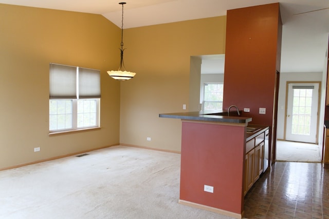 kitchen with kitchen peninsula, vaulted ceiling, sink, pendant lighting, and carpet floors