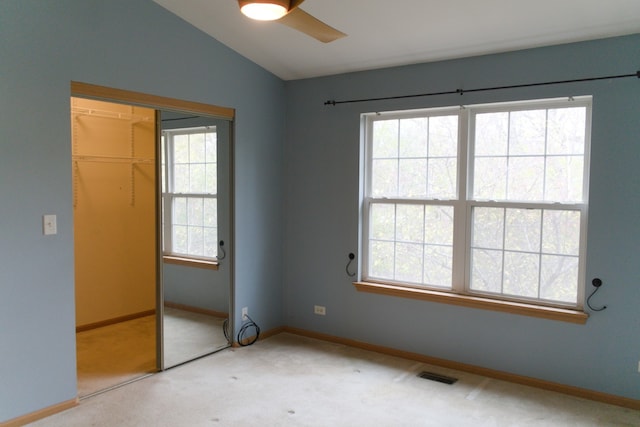 unfurnished bedroom with carpet, a closet, lofted ceiling, and ceiling fan