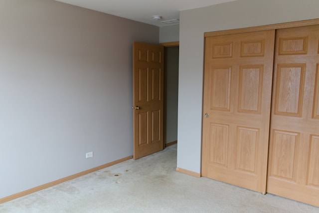 unfurnished bedroom featuring light colored carpet and a closet