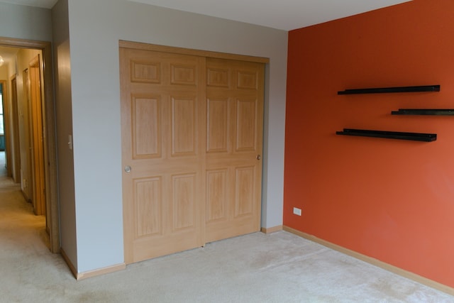 unfurnished bedroom with light colored carpet and a closet