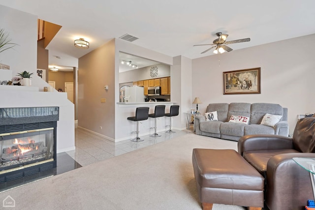 living room with a multi sided fireplace, light tile patterned floors, and ceiling fan