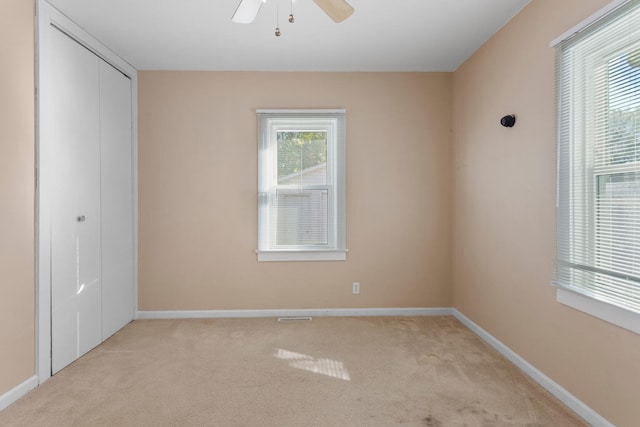 unfurnished bedroom with ceiling fan, light carpet, and a closet