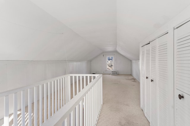 hallway featuring light colored carpet and lofted ceiling