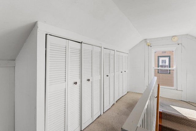 hall with lofted ceiling and light carpet