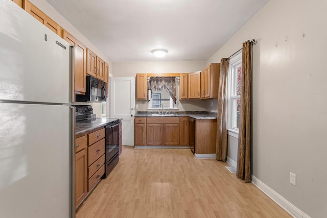 kitchen featuring light wood-type flooring, sink, and black appliances