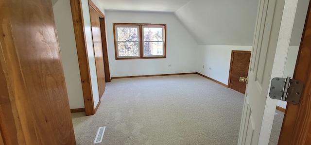 bonus room with lofted ceiling and light carpet