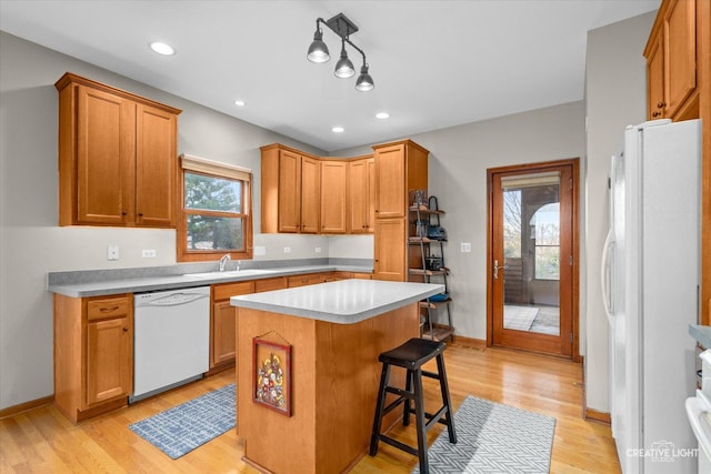 kitchen with plenty of natural light, a kitchen island, white appliances, and light wood-type flooring