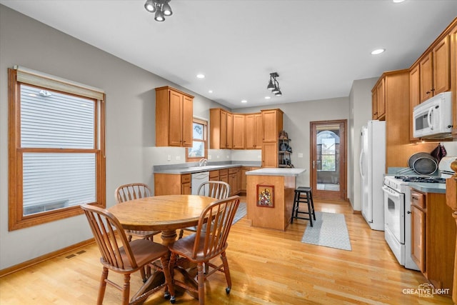 kitchen featuring a breakfast bar area, a center island, white appliances, and light hardwood / wood-style flooring