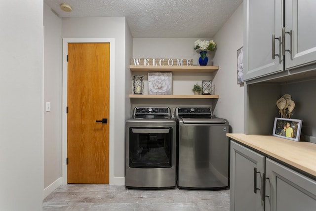 laundry room with separate washer and dryer, cabinets, and a textured ceiling