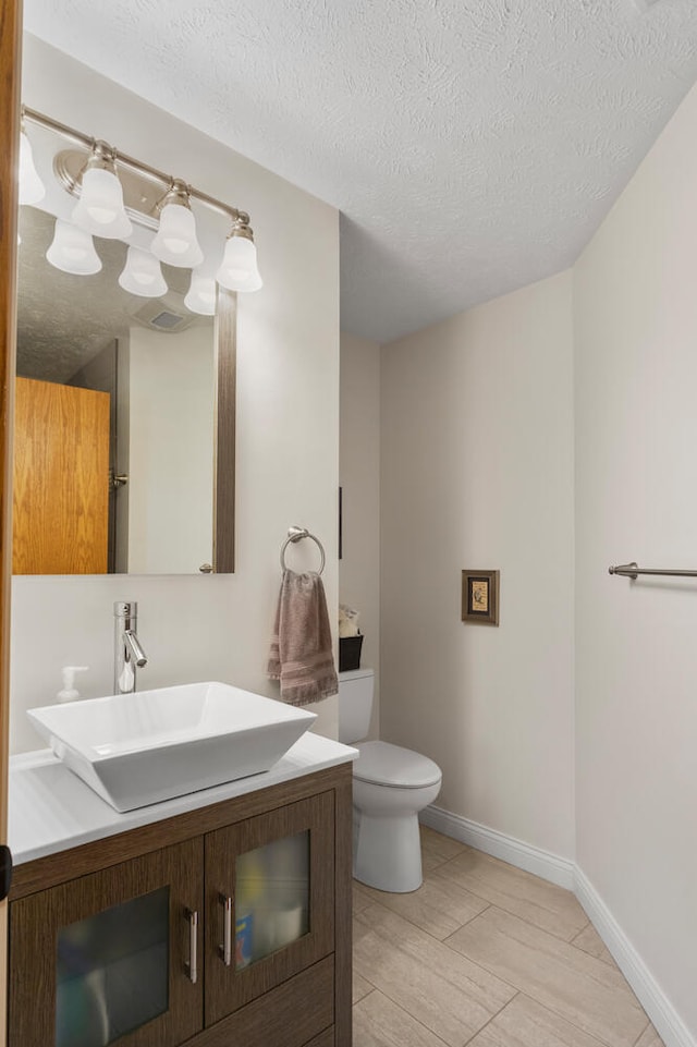 bathroom with vanity, a textured ceiling, and toilet