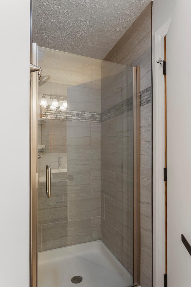 bathroom with walk in shower and a textured ceiling