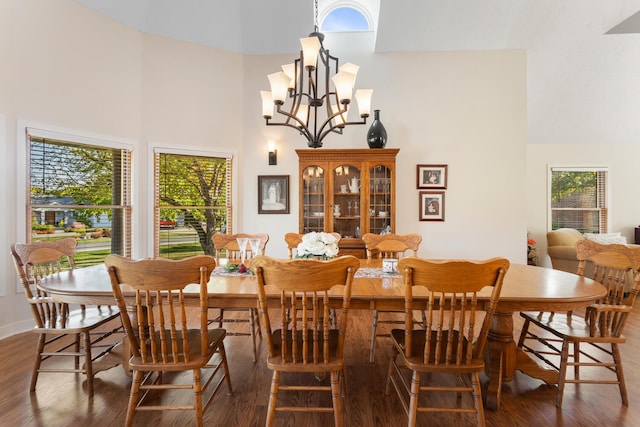 dining area featuring a wealth of natural light, a towering ceiling, and an inviting chandelier