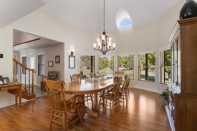 dining room with an inviting chandelier, plenty of natural light, a high ceiling, and dark hardwood / wood-style flooring