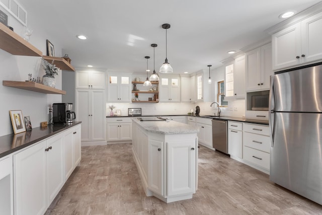 kitchen featuring light wood-type flooring, a center island, white cabinets, pendant lighting, and appliances with stainless steel finishes