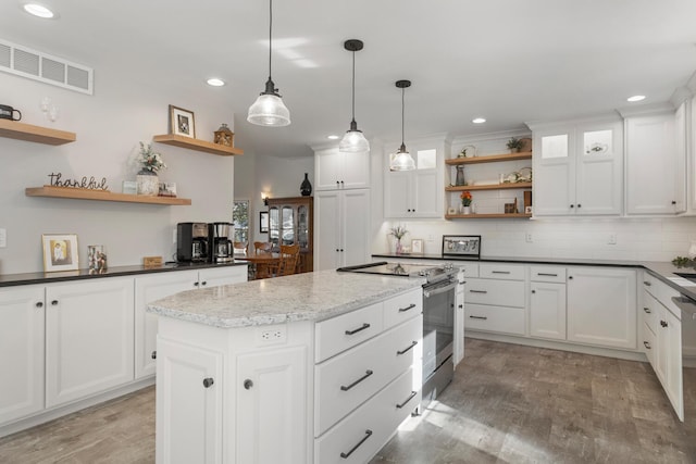 kitchen with decorative light fixtures, electric stove, and white cabinetry