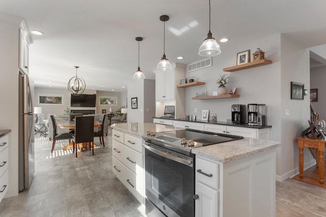 kitchen with decorative light fixtures, stainless steel appliances, light wood-type flooring, and white cabinetry