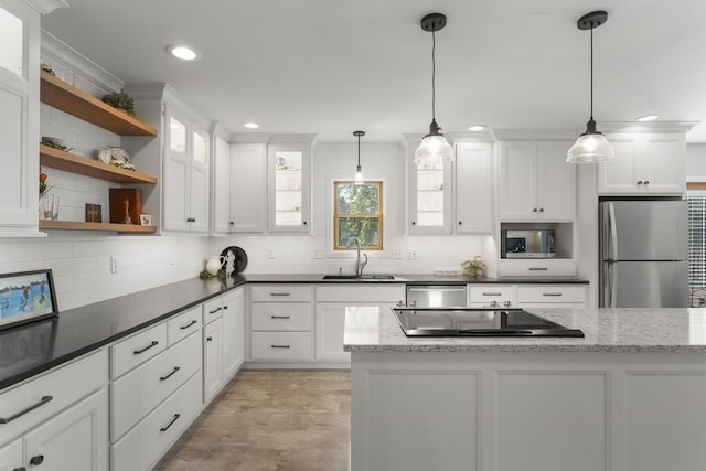 kitchen with stainless steel appliances, dark stone countertops, sink, hanging light fixtures, and white cabinetry